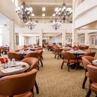 A spacious dining room with elegant chandeliers and neatly arranged tables and chairs.
