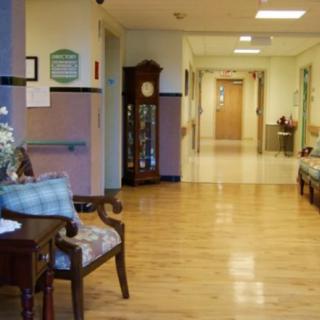 A hospital hallway with wooden flooring and seating area.