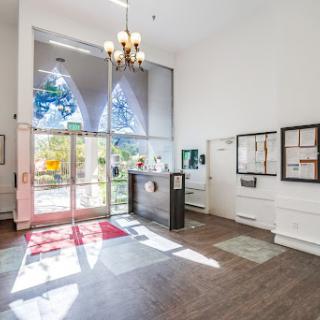 A spacious and bright lobby featuring modern design elements, large windows, and a stylish chandelier.