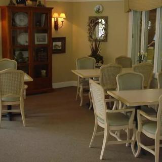 A cozy dining area with multiple tables and chairs, softly lit by wall sconces.