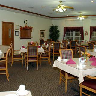 An empty dining room with neatly set tables and chairs, well-lit by ceiling lights.