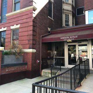 Entrance to a brick building with an awning and ramp access.