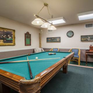 A cozy recreation room featuring a pool table, comfortable seating, and decorative wall art.