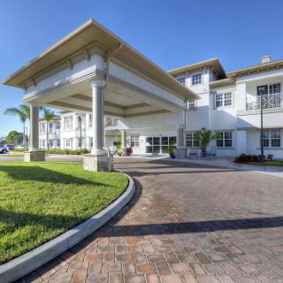 A grand entrance of a modern building with a covered driveway and landscaped surroundings.