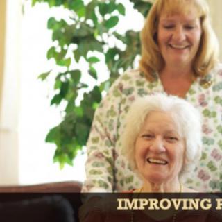 A caregiver smiling with an elderly woman indoors.