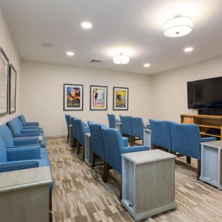 A modern theater room with blue seating and a large screen ready for viewing.