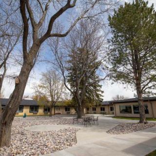 A serene courtyard with trees and a surrounding building under a partly cloudy sky.