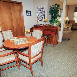 Cozy living space with a round table, chairs, and a piano.