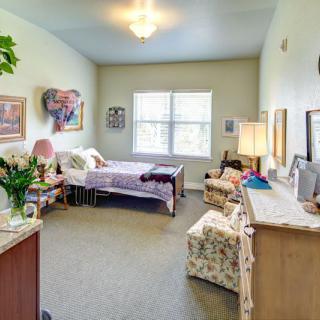A cozy and well-decorated bedroom with a single bed, comfortable seating, and natural light from the window.