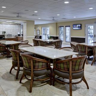 A spacious dining area with tables and chairs, featuring a television and warm lighting.