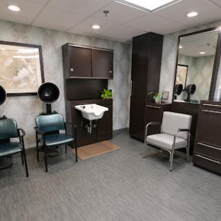 A stylish and modern waiting area in a salon, featuring comfortable seating and hair drying stations.