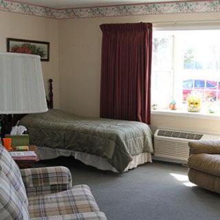 A cozy bedroom with a bed, armchair, and window with curtains.