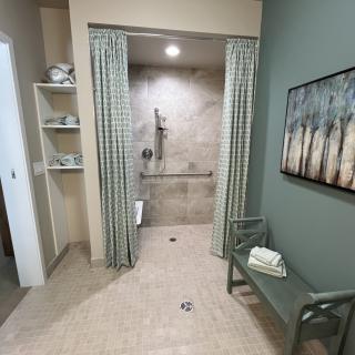 A modern bathroom with a spacious shower area, curtains, and neatly organized shelves.
