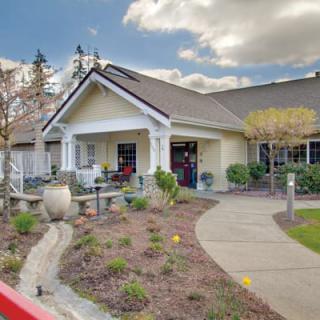 A charming home with a beautifully landscaped garden and a clear path under a cloudy sky.