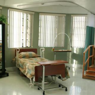 A hospital room equipped with a medical bed and rehabilitation equipment.
