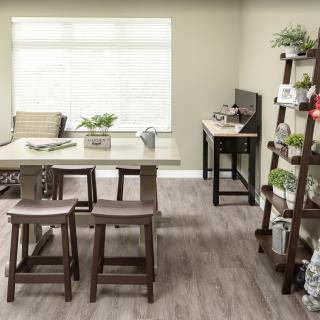 A well-lit dining area with a table and chairs, surrounded by shelves filled with plants and decor.