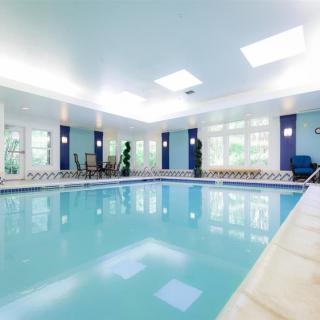 A modern indoor swimming pool with large windows and bright lighting.