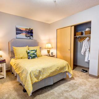 A cozy bedroom with yellow bedding and an open closet.