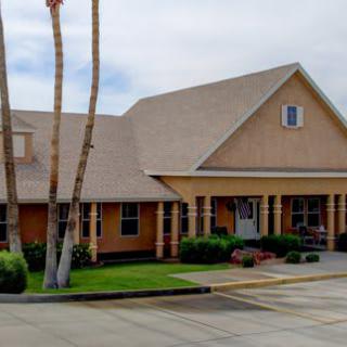 A residential house with a sloped roof and palm trees in the front yard.