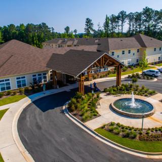 Aerial view of a building with a circular driveway and fountain at the entrance.
