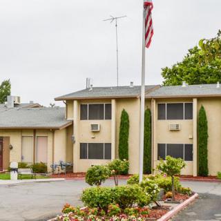 A two-story building with a flagpole and landscaped surroundings.
