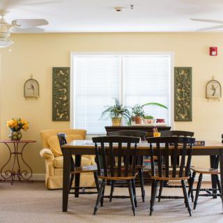 A cozy dining area with a wooden table and chairs, complemented by indoor plants and decorative wall art.