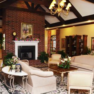 A traditional living room with a brick fireplace, elegant sofas, and a chandelier.