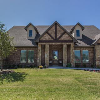 A brick suburban house with a neatly maintained lawn and a clear blue sky.