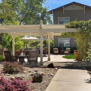 A beautiful backyard patio with a pergola and outdoor seating, surrounded by lush landscaping.