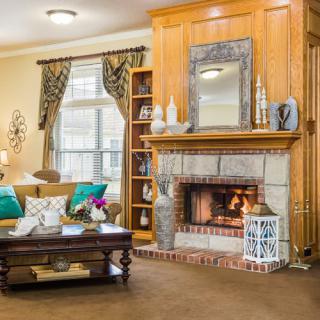 A cozy living room featuring a wooden fireplace, decorative mirror, and elegant furnishings.