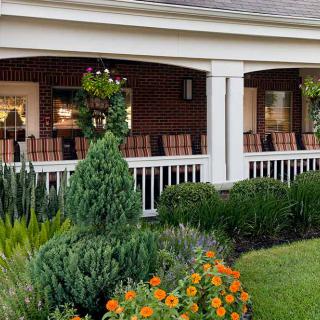 A charming porch surrounded by a well-maintained garden with vibrant flowers.