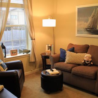 A cozy living room with a sofa, armchair, and warm lighting.