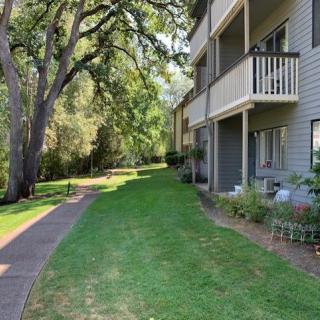 Apartment building with balconies and a grassy area alongside a sidewalk.