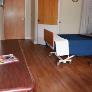 Simple hospital room interior with a bed and table.