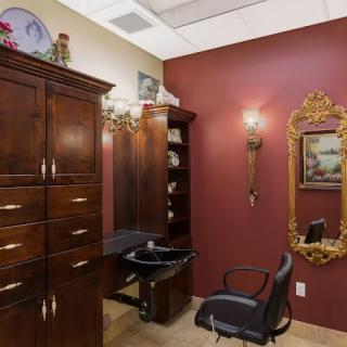 A stylish salon interior with a chair, mirror, and wooden cabinets.