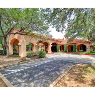 A building with an arched entrance surrounded by trees and a parking lot.