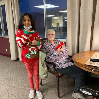 A heartwarming moment between a child and an elderly woman, both in festive attire.