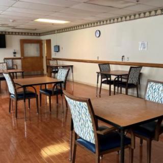 An empty dining room with multiple tables and chairs arranged neatly on a wooden floor.