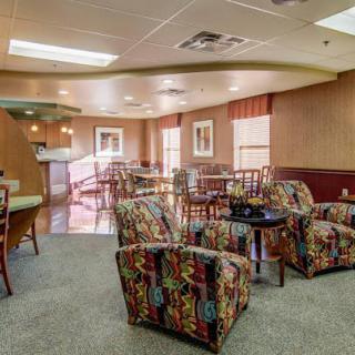 A cozy lobby with colorful chairs and tables, featuring carpeting and artwork on the walls.