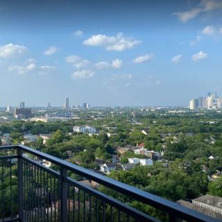 A scenic view from a balcony overlooking an urban area with buildings and greenery under a clear blue sky.