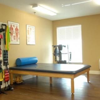 A physical therapy room equipped with exercise mats, resistance bands, and anatomical charts.