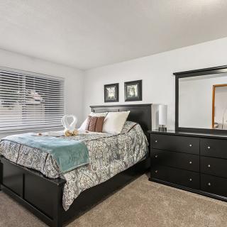 A modern bedroom with a neatly made bed and matching dresser set.