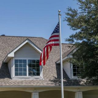 A suburban house with an American flag flying outside under a clear blue sky.