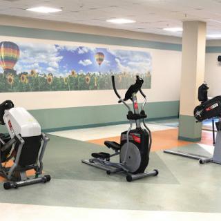 A view of a gym featuring various exercise equipment, including an elliptical machine and stationary bike.
