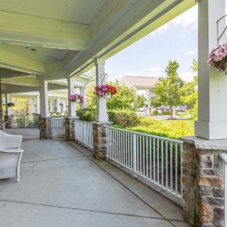 A sunny porch with hanging flower baskets overlooking a garden path.