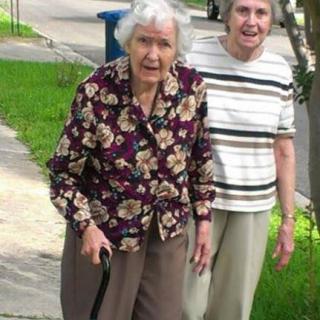 Two elderly women walking together outdoors.