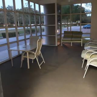 A modern waiting area featuring several chairs and large glass windows allowing natural light.