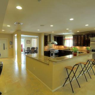 A modern open-plan kitchen with bar stools and ample lighting.