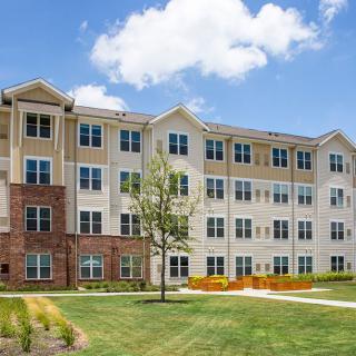 A modern apartment building with well-maintained landscaping and clear blue skies.