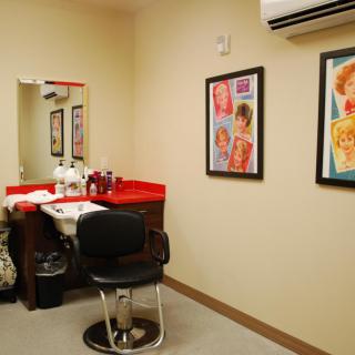Interior of a hair salon with a chair, mirror, and hair products on the counter.